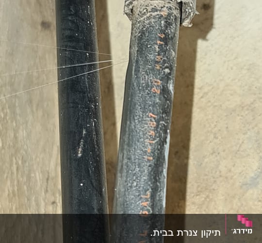 צינור שחור עם כיתוב אדום על רקע קיר